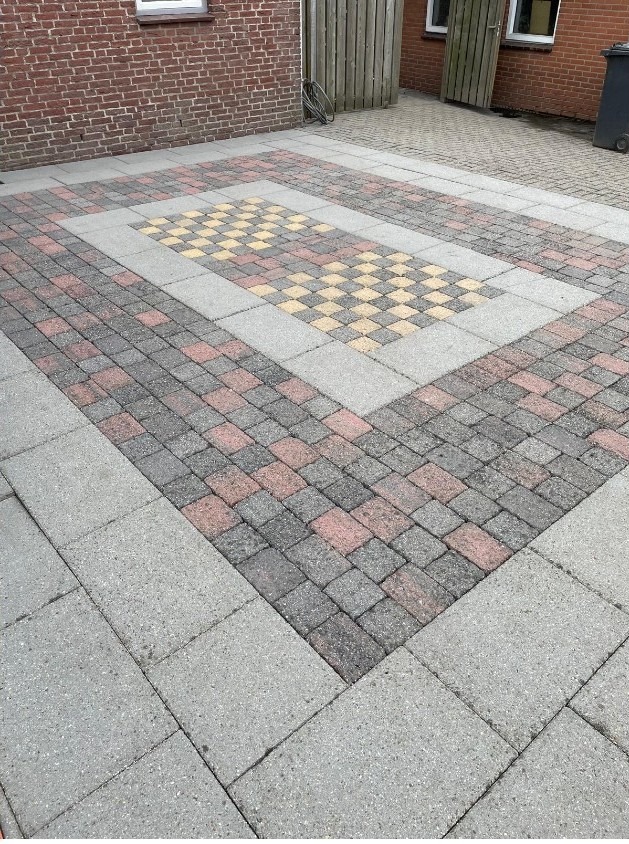 Hetzelfde terras na de reiniging, de rode en gele stenen weer goed zichtbaar