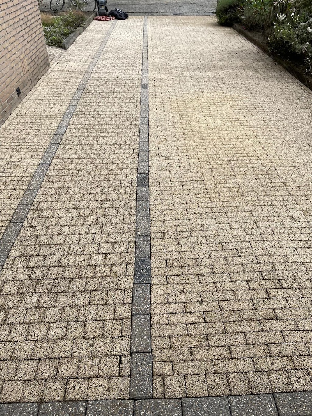 Gereinigde oprit van gele klinkers met een donkere streep, weer licht van kleur