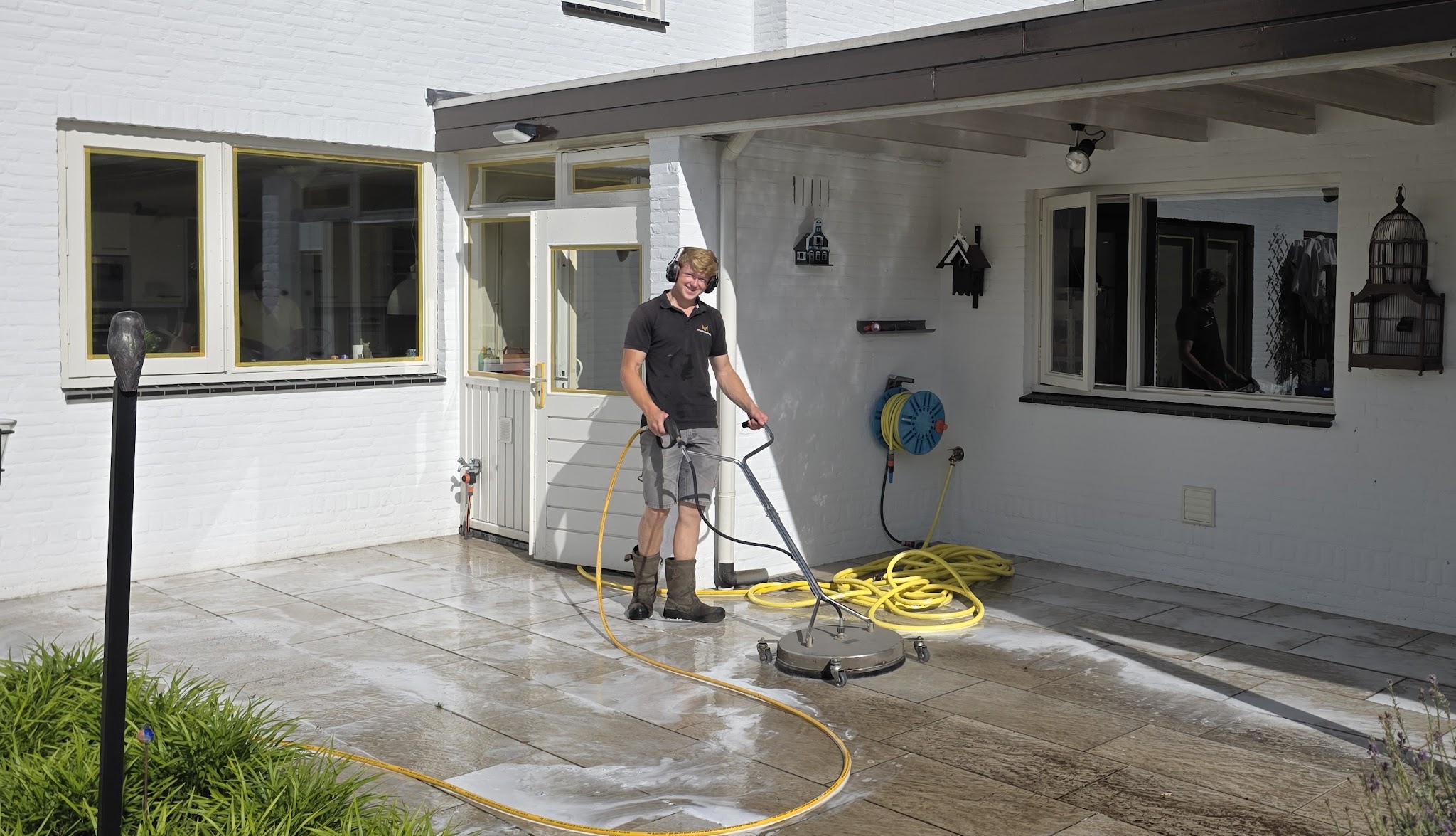 Mike aan het werk met een terrasreiniger onder een overkapping