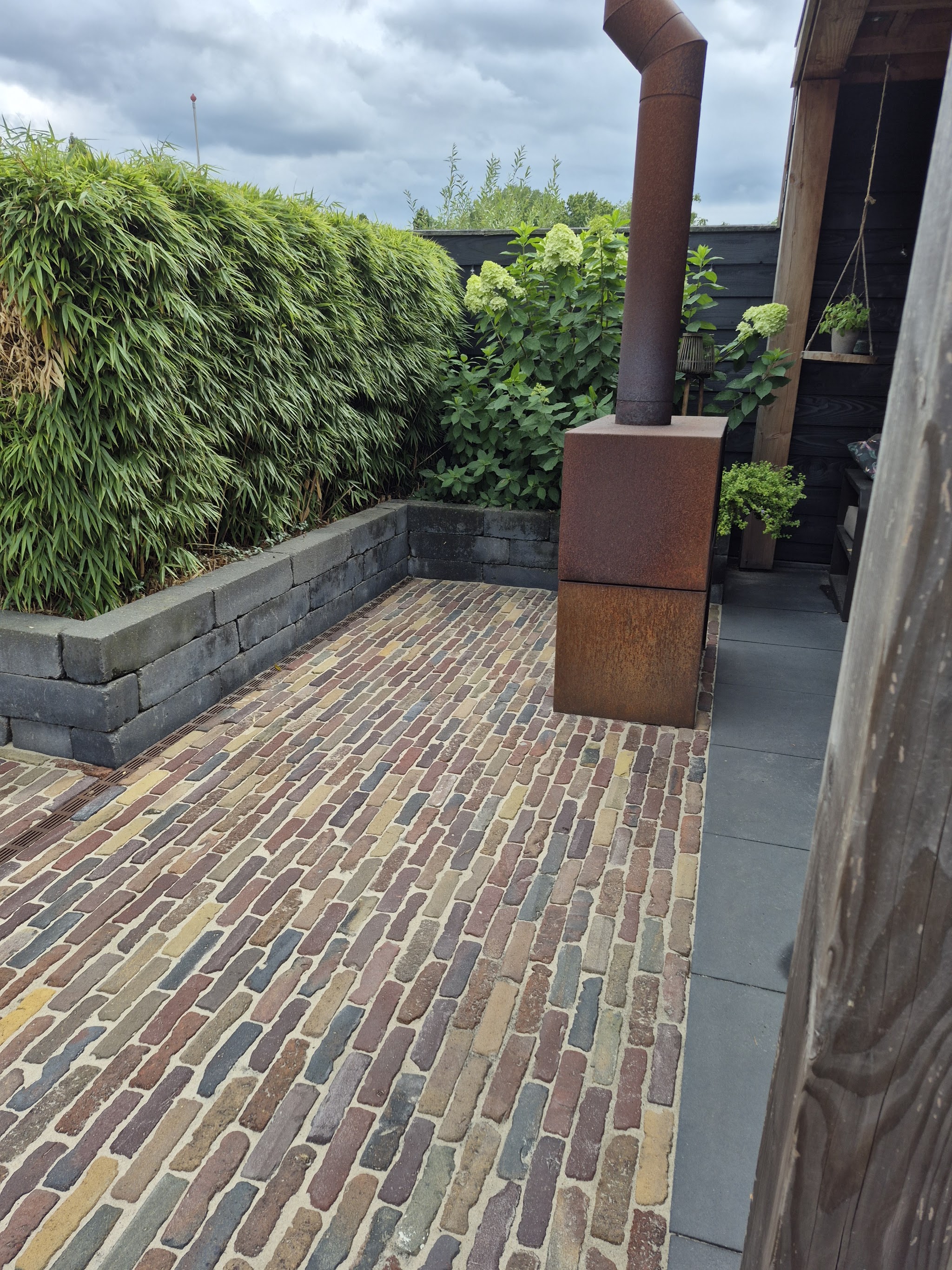 Schoongemaakt terras van gebakken klinkers in een tuin met bamboe