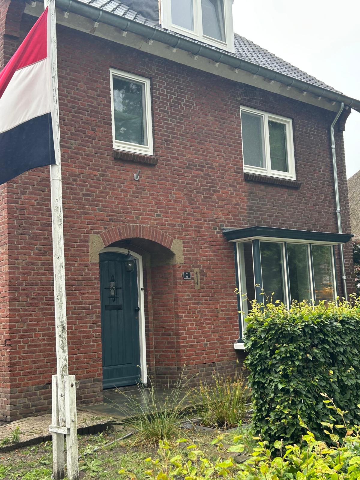 Bakstenen woning met schone gevel en een groene voordeur